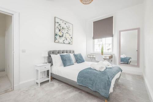 a white bedroom with a bed and two mirrors at Skye Sands - The Eden Residence in St. Andrews