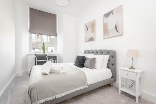 a white bedroom with a bed and a chair at Skye Sands - The Eden Residence in St. Andrews