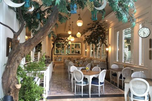 a restaurant with tables and chairs and a tree at Noor Hotel in Bandung