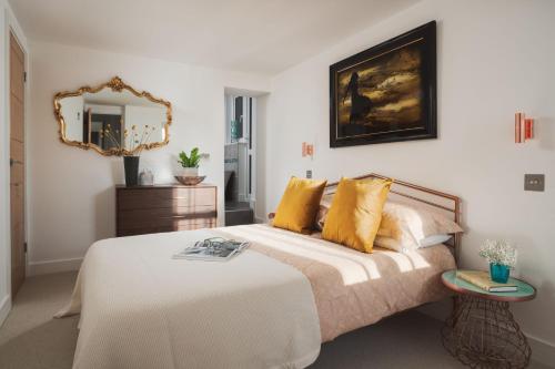 a bedroom with a bed with yellow pillows and a mirror at Blue Horizon in Portloe