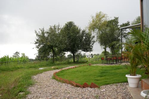 a garden with a gravel path and trees in the background at The Solace Bir in Bīr