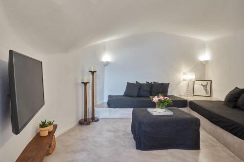 a living room with a couch and a tv at Arvanitis Cave Village in Akrotiri