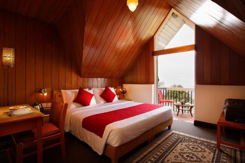 a bedroom with a bed and a desk and a window at Sterling Darjeeling in Darjeeling