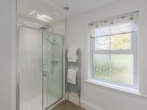 a bathroom with a glass shower and a window at 5 Bed in Bude 79454 in Milton Damerel