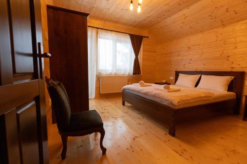 a bedroom with a bed and a chair in a cabin at Cabana Magura Belis in Călăţele