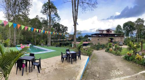un jardín con mesas y sillas y una piscina en El piedron, en Bogotá