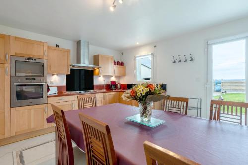 une cuisine avec une table avec un vase de fleurs dessus dans l'établissement Maison vue mer 150m de la plage, à Trégunc