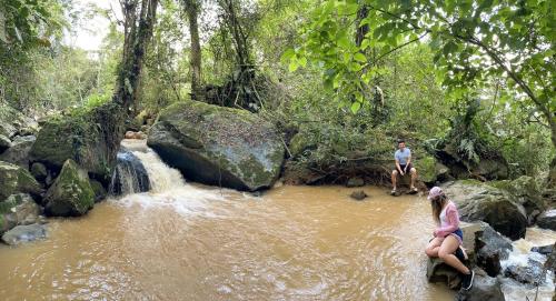 a man and a woman sitting on rocks in a river at El piedron in Bogotá