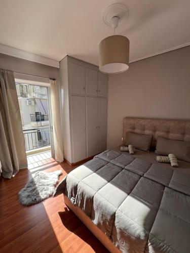 een slaapkamer met een groot bed en een groot raam bij TopCentral Apartment in Larisa