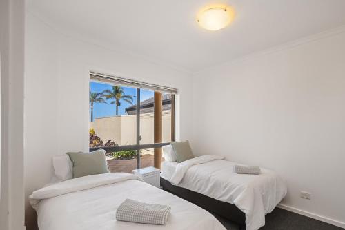 two beds in a room with a view of the beach at Waterfront Villa Provence in Port Lincoln