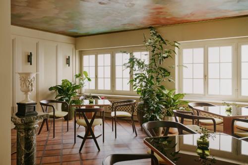 a dining room with tables and plants and windows at Locke am Platz Zurich in Zürich