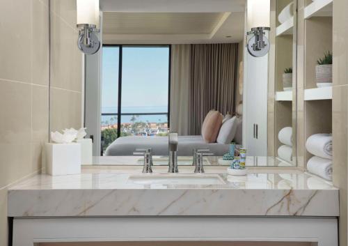 a bathroom with a sink and a large mirror at Hotel La Jolla, Curio Collection by Hilton in San Diego