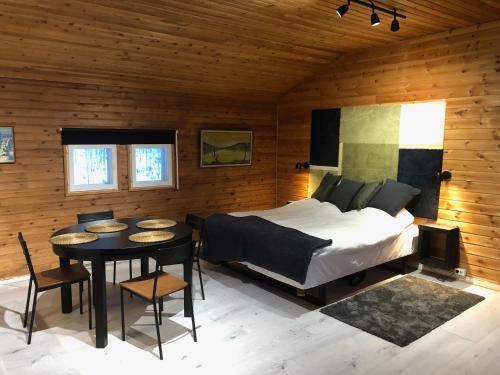 Kätkä Lake Lodge في Tervola: غرفة نوم بسرير وطاولة في غرفة