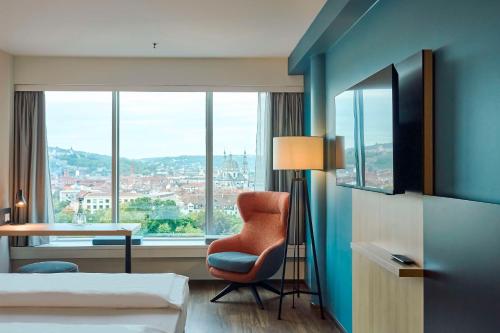 una camera d'albergo con sedia e finestra di GHOTEL hotel & living Würzburg a Würzburg