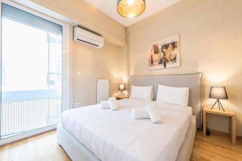 uma cama branca num quarto com uma grande janela em Syntagma H&B Apartment em Atenas