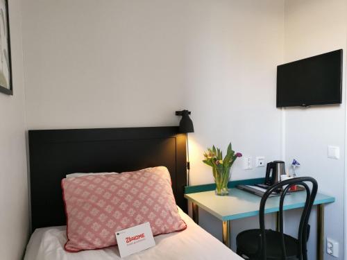 a bedroom with a bed and a desk with a phone at 2Home Hotel Gävle in Gävle