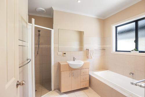 a white bathroom with a sink and a tub and a sink at Waterfront Villa Provence in Port Lincoln