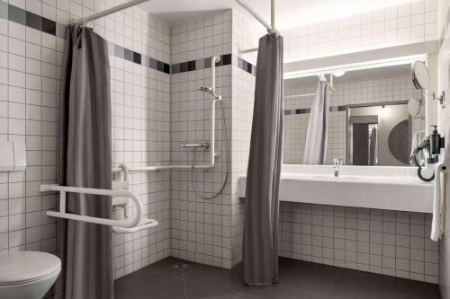 La salle de bains est pourvue d'une douche, d'un lavabo et de toilettes. dans l'établissement Vienna House Easy by Wyndham Günzburg, à Guntzbourg