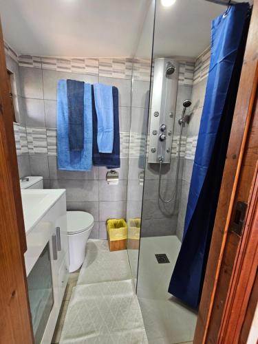 La salle de bains est pourvue d'une douche et de serviettes bleues. dans l'établissement La Maxada Luz Maria, à El Cotillo