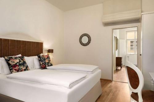 a white bedroom with a bed and a mirror at Amedia Plaza Wels, Trademark Collection by Wyndham in Wels