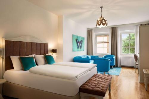 a bedroom with a large bed and blue chairs at Amedia Plaza Wels, Trademark Collection by Wyndham in Wels