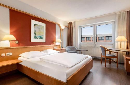a hotel room with a bed and a desk and a table at Amedia Weiden, Trademark Collection by Wyndham in Weiden