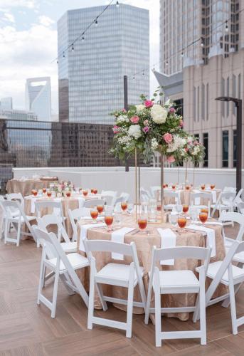 a group of tables with white chairs and flowers on a rooftop at DoubleTree by Hilton Charlotte City Center in Charlotte