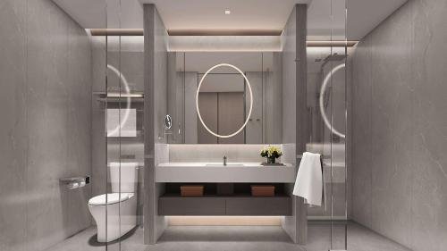 een badkamer met een wastafel, een toilet en een spiegel bij Yuexiu Hotel Guangzhou Curio Collection By Hilton, Free Shuttle during Canton Fair in Guangzhou