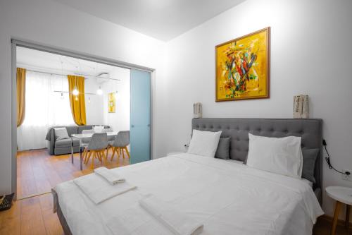 a bedroom with a large white bed and a dining room at Modern 2BD Flat with Prime Location and Workspace in Sofia