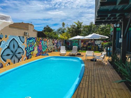 a swimming pool with chairs and a wall with graffiti at Innbox - Praia do Rosa in Praia do Rosa