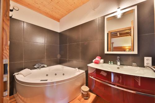 La salle de bains est pourvue d'une baignoire, d'un lavabo et d'un miroir. dans l'établissement Chambres d'hôtes Les Rondins De La Fecht, à Mittlach
