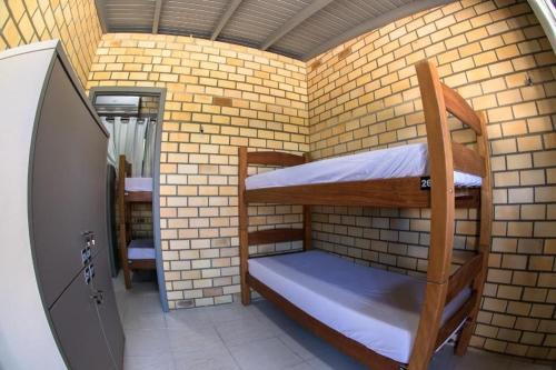 プライア・ド・ローザにあるInnbox - Praia do Rosaのレンガの壁に二段ベッドが備わる小さな客室です。