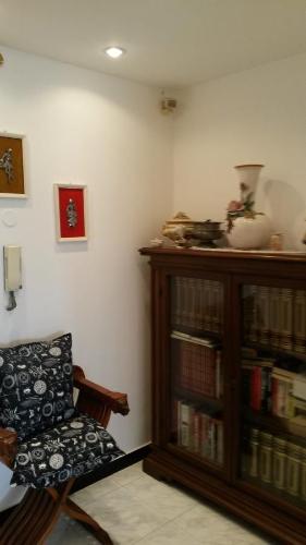 een kamer met een stoel en een boekenplank met boeken bij Appartamento Cavour 15 in Bogliasco