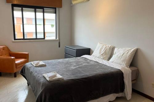 um quarto com uma cama com uma cadeira e uma janela em Cozy 2 Bedroom in Olhão em Quelfes