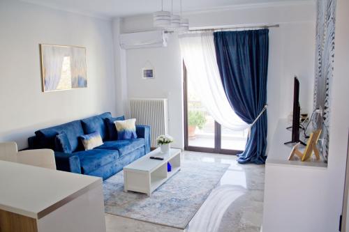 Ermis Mini Suite # 3 في خالكيذا: غرفة معيشة مع أريكة زرقاء ونافذة
