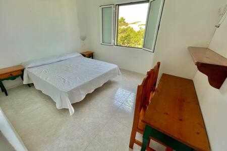 Zimmer mit einem Bett, einem Tisch und einem Fenster in der Unterkunft BoschApartamento de 2 dormitorios y con piscina in Ciutadella