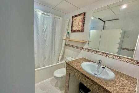 W łazience znajduje się umywalka, toaleta i lustro. w obiekcie BoschApartamento de 2 dormitorios y con piscina w mieście Ciutadella