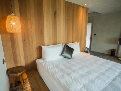 a bedroom with a white bed with a wooden wall at The Forest Museum in Zhuolan