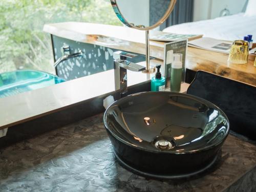 a black sink in a bathroom with a mirror at The Forest Museum in Zhuolan