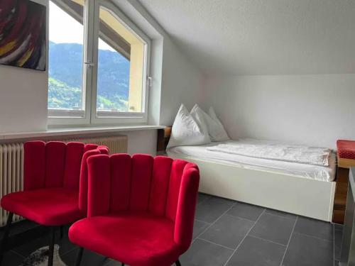 a room with red chairs and a bed and a window at Lake view appartment in Zell-am-See city centre in Zell am See