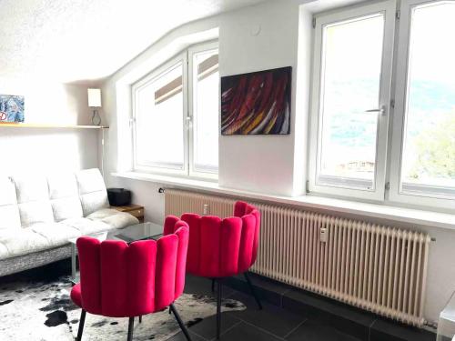 a living room with two red chairs and a couch at Lake view appartment in Zell-am-See city centre in Zell am See