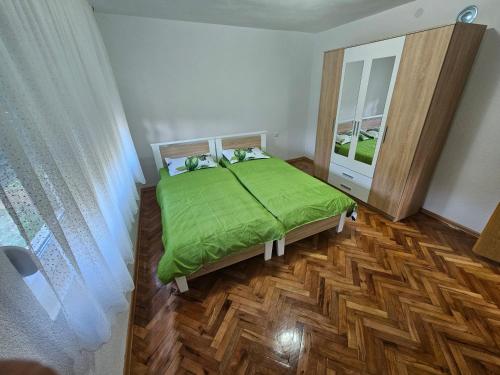 a bedroom with a green bed and a mirror at Apartman Capital Novi Grad in Bosanski Novi