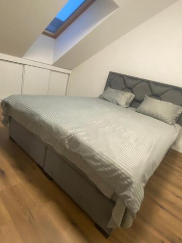 - une chambre dotée d'un grand lit avec des draps et des oreillers blancs dans l'établissement Apartman Harmonija, à Inđija