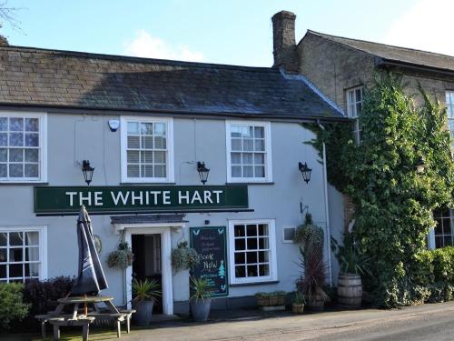 un bâtiment blanc avec un panneau qui lit le chapeau blanc dans l'établissement The White Hart Country Inn, à Fulbourn
