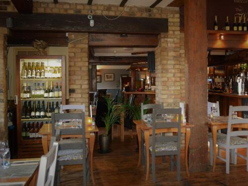un restaurante con mesas, sillas y botellas de vino en The White Hart Country Inn en Fulbourn