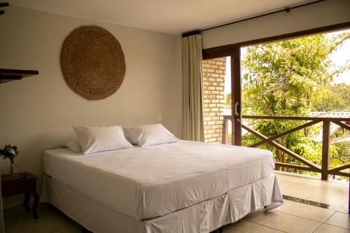 a bedroom with a bed and a large window at Pousada Mãe Natureza in Pipa