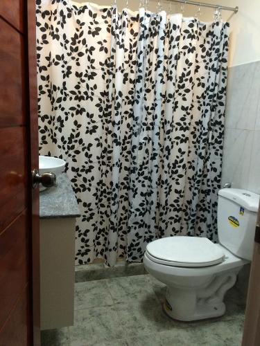 a bathroom with a toilet and a black and white shower curtain at Casa Roces in Legazpi