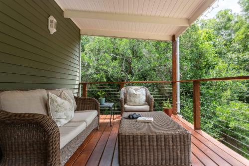 eine Veranda mit einem Sofa und Stühlen auf einer Terrasse in der Unterkunft Forest Glades in Knysna