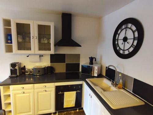 una cocina con un reloj grande en la pared en Agréable maison 8 personnes WIFI et clim, en Marmeaux