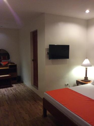 a hotel room with a bed and a flat screen tv at Casa Roces in Legazpi
